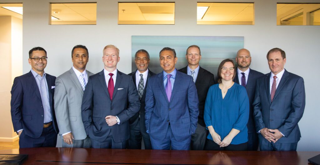 Nine leadership members standing together behind an office table
